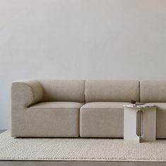 a beige couch sitting on top of a white rug