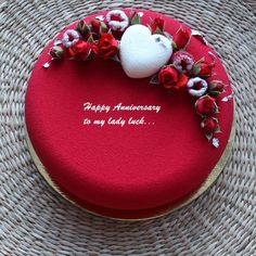 a red cake decorated with flowers and an apple on top that says happy anniversary to my lady luck