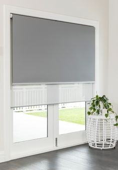 a large window with blinds on it and a potted plant next to it