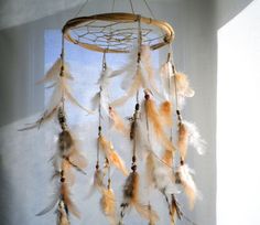 a dream catcher with feathers hanging from it's side in front of a window