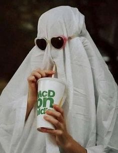 a person in a ghost costume holding a cup