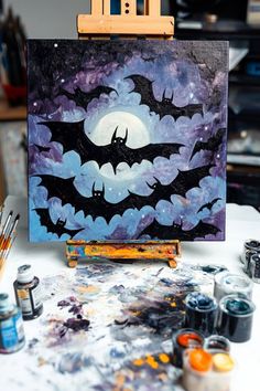 a bat painting on an easel with paintbrushes and other art supplies around it