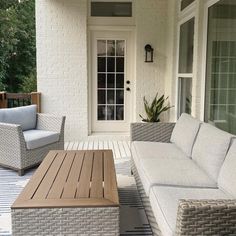 an outdoor living area with couches and tables on the deck, next to a door