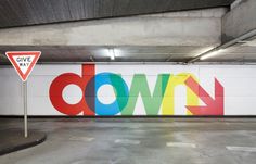 an empty parking garage with the word down painted on it's side and a give way sign next to it