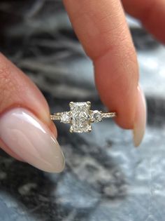 a woman's hand holding a diamond ring