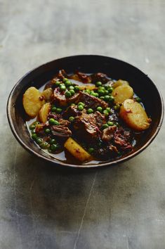 a brown bowl filled with meat and peas