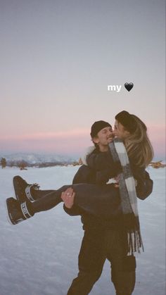 two people standing in the snow with one woman holding her back and kissing another man's forehead