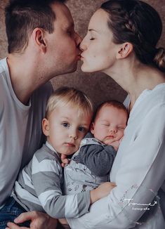 a man and woman kissing their baby boy