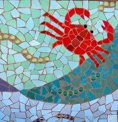 a red crab sitting on top of a blue and green mosaic tile wall next to water