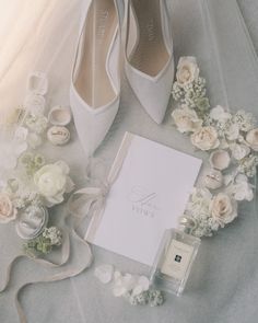 wedding shoes, ring and note laid out on a bed next to the bride's bouquet