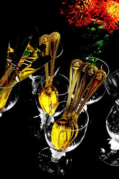 three wine goblets filled with yellow liquid next to a red and yellow flower