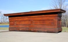 an old wooden box sitting on the side of a road in front of a lake