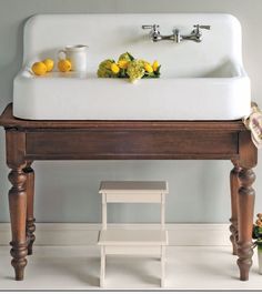 a white sink sitting next to a wooden table with two lemons on top of it