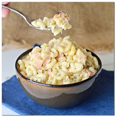 a spoonful of macaroni and cheese is being lifted from a bowl on a blue napkin