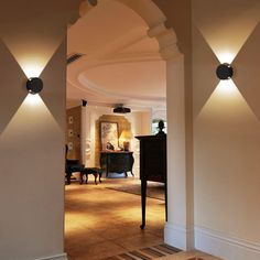 an archway leading to a living room with piano in the corner and lights on either side