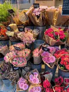 a bunch of flowers that are sitting on a table in front of some bags and buckets