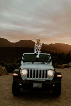 a woman sitting on the hood of a jeep