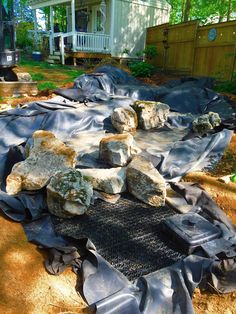 some rocks laying on top of a tarp in front of a house and trees