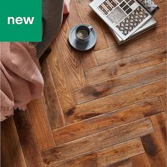 a coffee cup on a wooden floor next to an open magazine and some other items