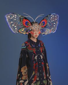 a woman with butterfly wings on her head wearing a blue shirt and black dress,