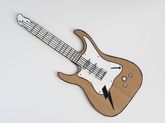 an electric guitar cut out from cardboard on a white surface with a lightning bolt in the middle