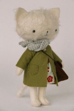 a white teddy bear wearing a green coat