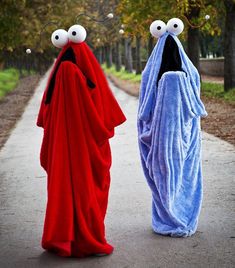 two people dressed in costumes walking down a path with eyes on their faces and mouths open