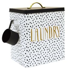 a white and black polka dot laundry box with gold lettering on the lid, hanging from a hook