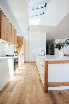 a kitchen with wooden flooring and white walls next to a skylight above the counter