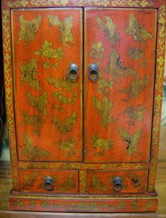 an orange cabinet with gold flowers painted on it