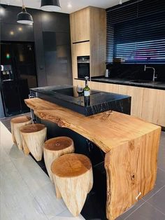 a kitchen with black counter tops and wooden stools in front of an island made out of wood