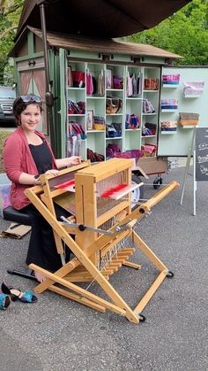 a woman sitting in front of a table with a weaving machine on top of it