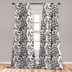 black and white floral curtains hanging on a window sill in front of a wooden floor