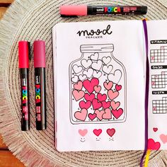 a notebook with hearts in a jar on it next to markers and marker pens,