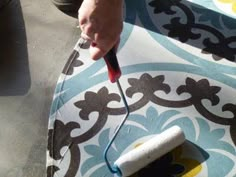 someone using a paint roller on a patterned rug