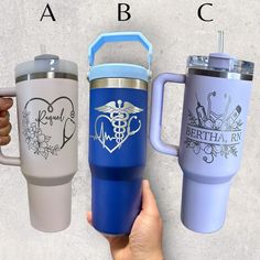 three travel mugs with the names of different medical subjects on them, one is blue and one is gray