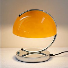 an orange table lamp sitting on top of a white countertop next to a black cord