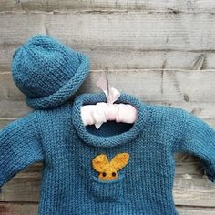 a knitted sweater with a hoodie on it and a stuffed animal in the back