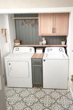 a washer and dryer in a small room with wood cabinets on the wall