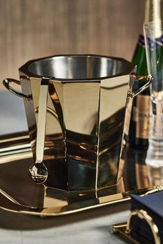 a tray with two champagne glasses and a silver cup on it, next to bottles of wine