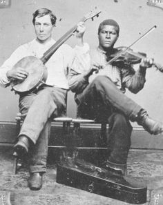 two men sitting next to each other holding musical instruments