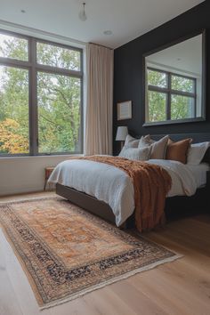 a large bed sitting next to a tall window in a bedroom on top of a hard wood floor