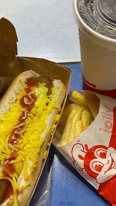 a hot dog with cheese and ketchup next to fries