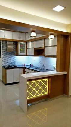 an empty kitchen with white cabinets and yellow lights on the countertop, along with stainless steel appliances