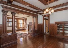 an empty living room with wood floors and wooden columns on the wall, along with large windows