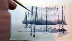 someone is holding a paintbrush and painting trees in watercolor on white paper with black ink