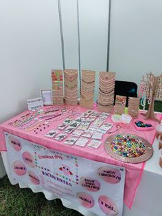 the table is set up with pink and white decorations on it, including cookies, doughnuts, and candy bars