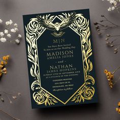 a wedding card with an intricate design and gold foil on the front, sitting next to flowers