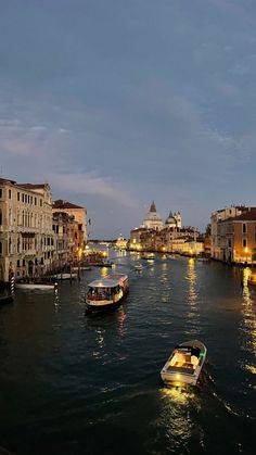 two boats are traveling down the river in venice, italy at night with lights on them