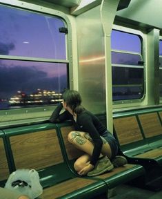 a person sitting on a bench in front of a window with the city lights behind them